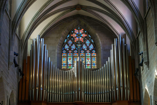 Beautiful old church organ in front of a stained glass window and arched ceiling