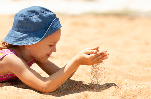 Girl wearing swimming goggles and playing in the sand on the beach