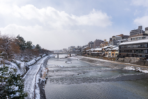 Snowy Kamo River ( Kamogawa ) in winter, Gion District, Kyoto, Japan. Ancient wooden houses on the riverbanks.