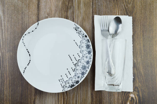 Glass, spoon, fork, tissue and plate over wooden background