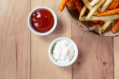 A top down view of two dipping condiments, featuring ketchup and mayonnaise.