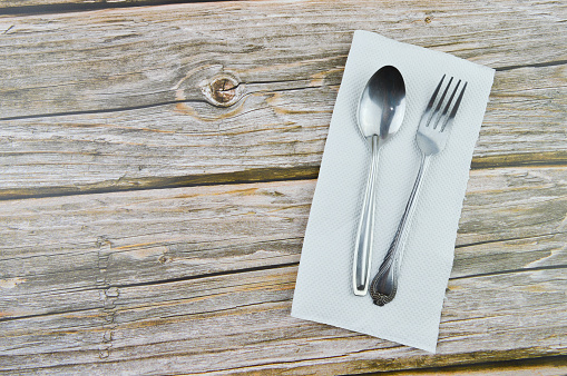 Spoon, fork and tissue over wooden background with copy space.