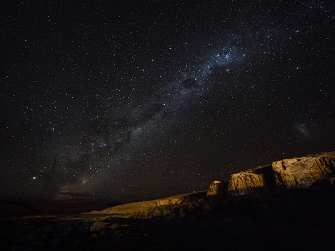 Panorama view of milkyway stars in dark night sky above cliff rock formation in Uyuni Sur Lipez Potosi Bolivia South America