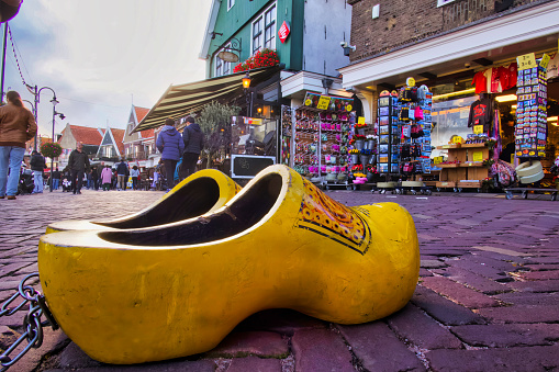 volendam, netherlands - 08 October 2022: giant wooden shoes on harbor front of dutch village with souvenir shops and terraces