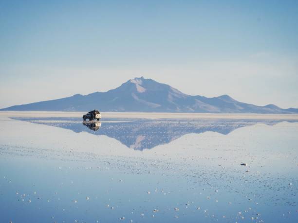 Offroad car SUV jeep of tour group on Salar de Uyuni salt flat lake in Bolivia andes mountains sunrise mirror reflection Andes mountains sunrise panorama mirror reflection on Salar de Uyuni salt flat lake in Potosi Bolivia, South America salar de uyuni stock pictures, royalty-free photos & images