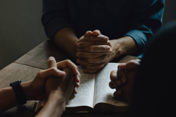 istock Christians and Bible study concept. Christians held each other's hands praying together and seeking the blessings of God,  They were reading the Bible and sharing the gospel. praying worship believe. 1461493336