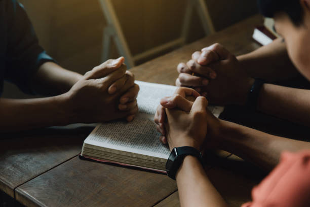 istock Christians and Bible study concept. Christians held each other's hands praying together and seeking the blessings of God,  They were reading the Bible and sharing the gospel. praying worship believe. 1461493348