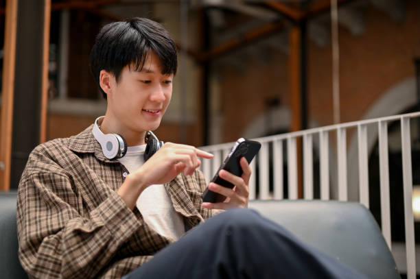 istock Handsome Asian man using his smartphone, chilling at the cafe. mobile app, network 1461496925