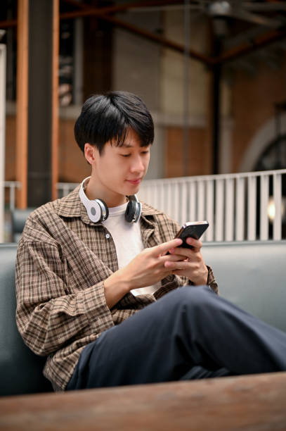 istock Handsome Asian man using his smartphone, chatting with his friends, chilling at the cafe. 1461496942
