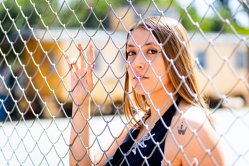 Portrait of young woman behind a wire fence.