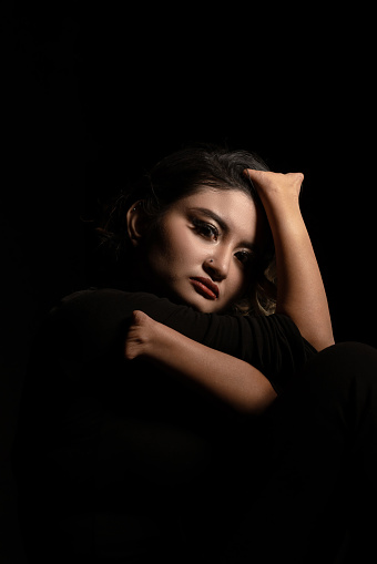 Moody and conceptual black-and-white beauty portrait of a Malay young woman without hands in a studio