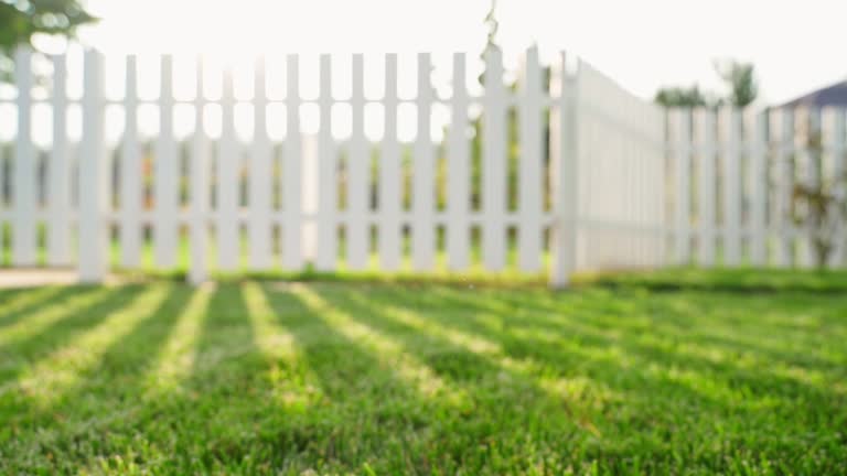 Lawn with a green mowed lawn on a warm summer day. Sun glare through the fence. Smooth camera movement over green grass. Blurred background