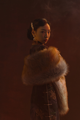 Side viewed beautiful chinese woman in shanghai tang qipao photographed in a studio portrait setting