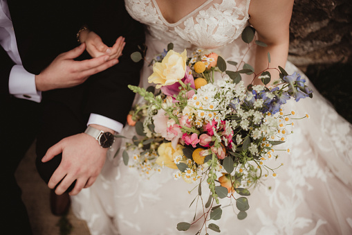 Bride and groom sitting down and holding a bouquet of flowers