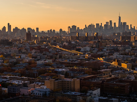 Remote view of the Lower Manhattan Skyline illuminated in the night over the residential district of Bushwick, Brooklyn, at the sunset.