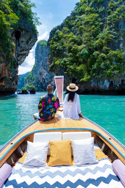 クラビタイのロングテールボート、熱帯の島4島での旅行でカップルの男性と女性 - thailand beach longtail boat cliff ストックフォトと画像