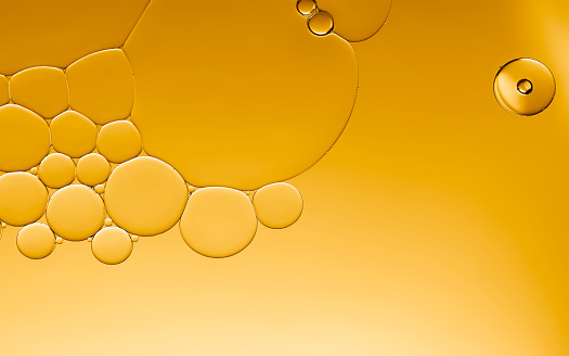 Art image of oil and water droplets bubbles serum seamless pattern on golden light effects texture background.