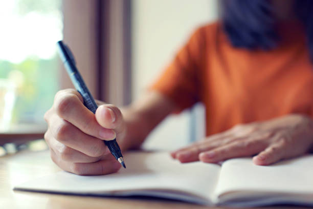 istock Close up woman hand writing on notebook . 1461537122