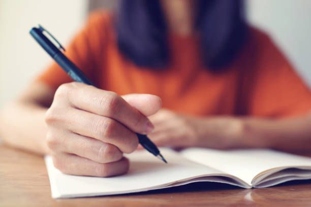 istock Close up woman hand writing on notebook . 1461537123