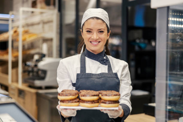 istock A happy baker is holding tray with doughnuts and offering them to a customers while standing at supermarket and smiling at the camera. 1461539675