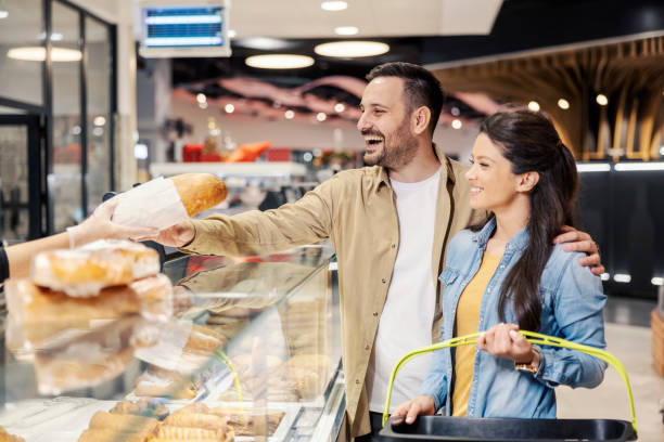 A happy couple is buying bread at bakery department in supermarket. stock photo
