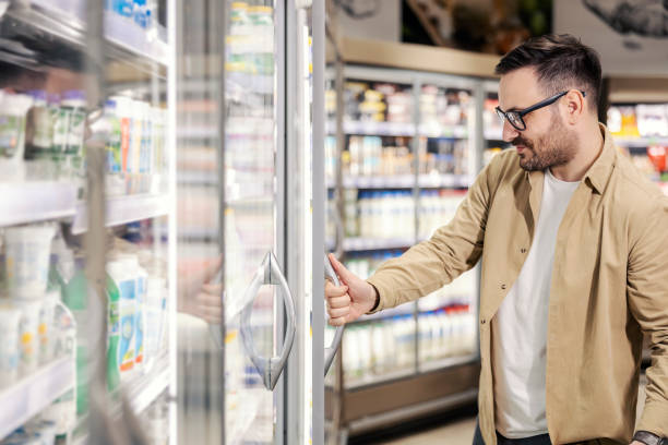 istock A smiling man is choosing products from fridge and opening it while standing on supermarket. 1461540648