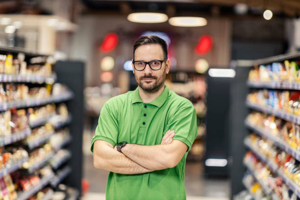 A successful salesman is standing with arms crossed at the marketplace and looking seriously at the camera. stock photo