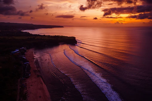 Aerial view of colorful sunset or sunrise and ocean with waves in Bali.