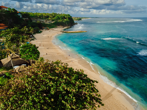 Tropical beach with turquoise ocean and waves in Bali island. Aerial view