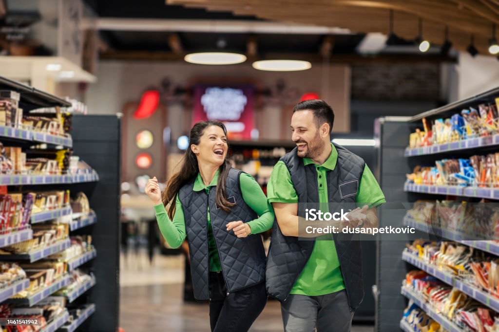 Joyful supermarket workers are dancing at marketplace. Happy supermarket workers are dancing and having fun at marketplace. Supermarket Stock Photo