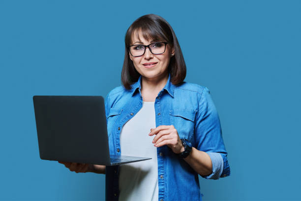 istock Mature business woman using laptop on blue background 1461543522