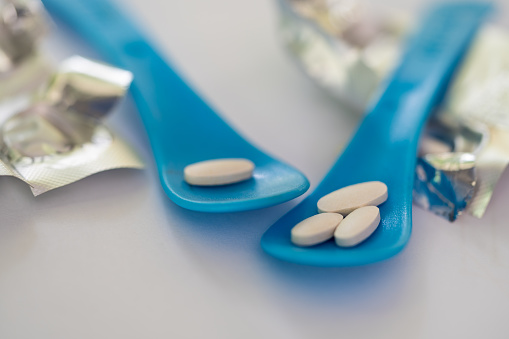 Close up a blue spoon and white pills medicine.