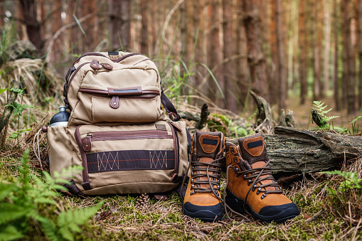 Hiking equipment in forest. Backpack and leather ankle boots
