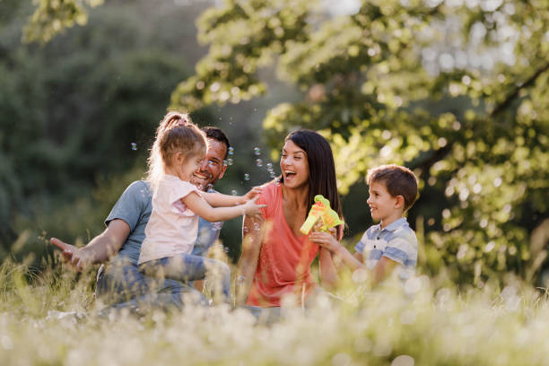 bonne famille profitant de la journée de printemps au parc. - bubble wand outdoors little boys mother photos et images de collection