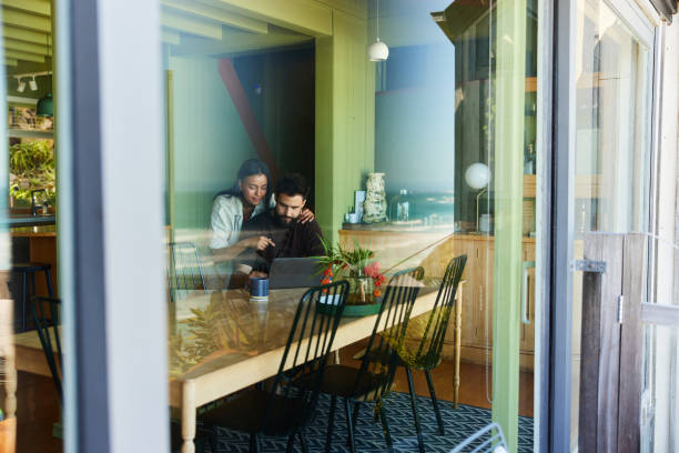 istock Young couple working on a laptop by a window at home 1461557888