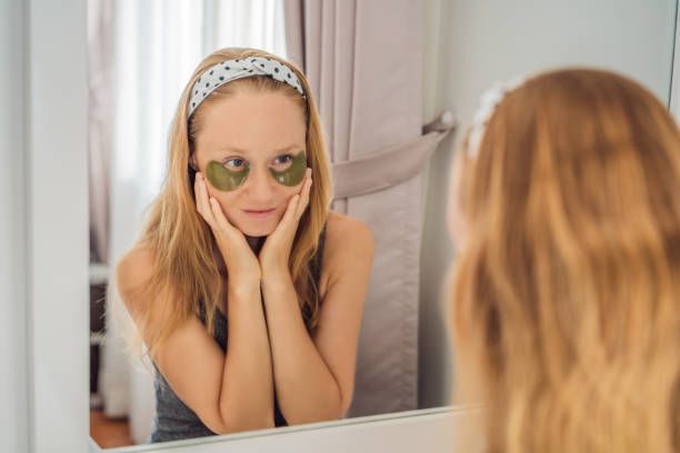 istock Mirror reflection smiling woman applying hydrogel eye care patches, moisturizing skin under eyes, enjoying skincare procedures 1461558738