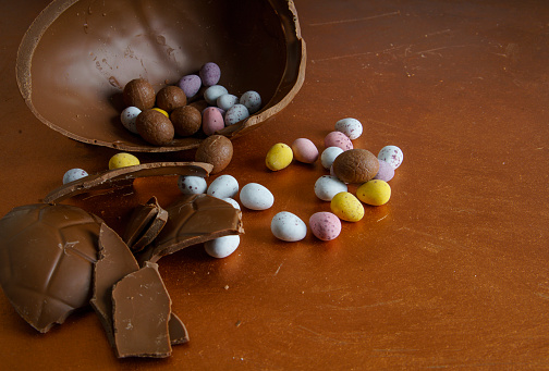 Broken chocolate easter eggs on a dark orange surface