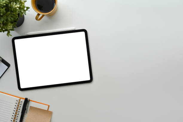 istock White working desk with digital tablet, notebooks and coffee cup. Blank display for your advertise design. 1461562519