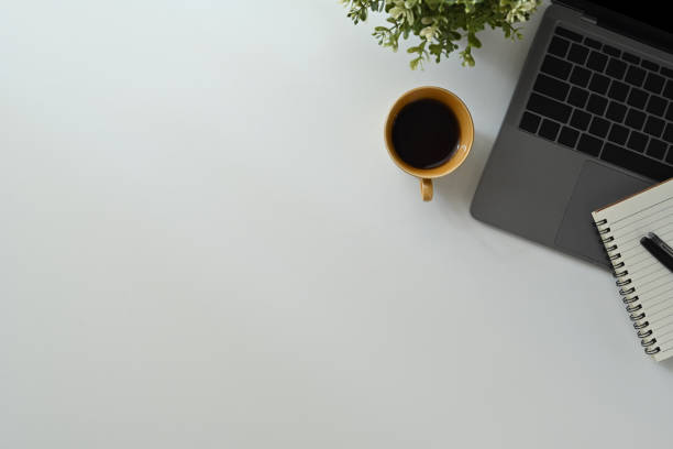 istock Laptop computer, cup of coffee and notebook on white office desk. Top view with copy space for your text. 1461562524