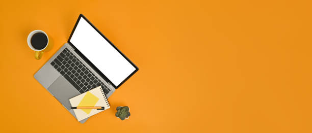 istock Mock up laptop computer with blank screen, notepad and coffee cup on yellow background. Copy space for your advertise text. 1461562640