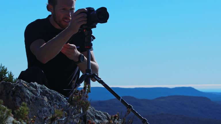 Fluid head tripod and camera being operated by a young man with blue sky in background