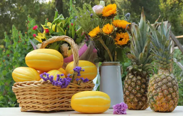 A closeup shot of fresh fruits in a basket and a vase with a bouquet