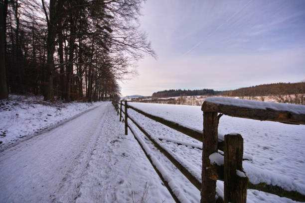 Frozen trail with a fence on a field in wintertime at Weissbach at the forest of Odes in Germany 01/31/2023