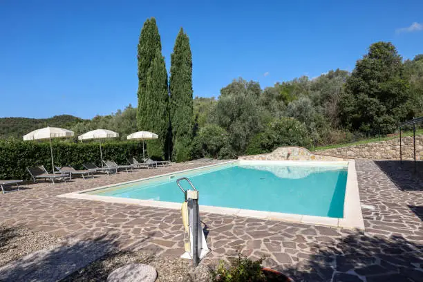 Photo of A swimming pool on the Montemassi hillside surrounded by cypresses and oleanders. Italy