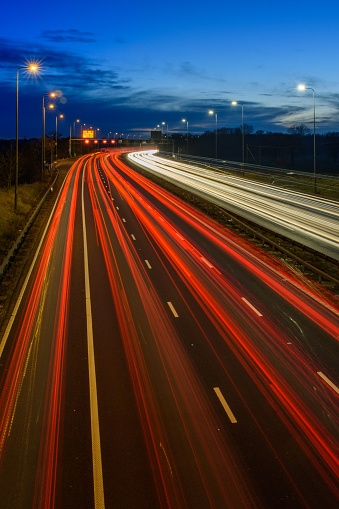 Speeding traffic on M42 motorway during evening rush hour leaves light trails and streaks due to slow shutter speed and long exposure photography.