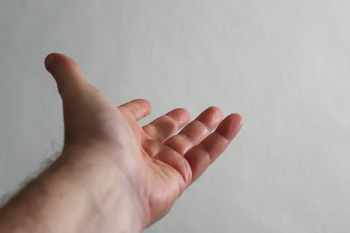 A male hand reaches towards a gray wall