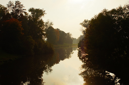 The river Nidda in the autumn evening light. Beautiful colours and reflections against the light in Frankfurt-Bonames.
