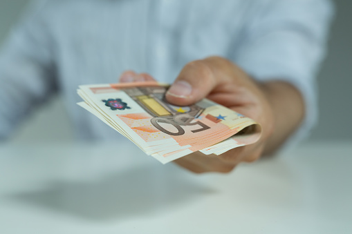 A selective focus of a male hand holding 50 euros in his hand - concept of business