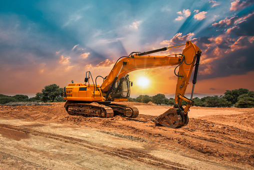 yellow excavator on the construction site at sunset