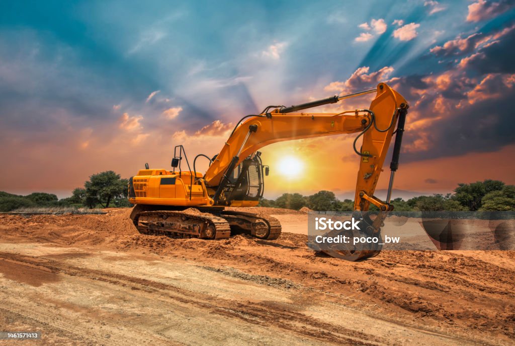 excavator at sunset yellow excavator on the construction site at sunset Construction Site Stock Photo